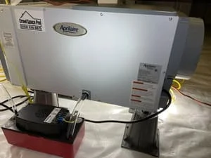 Aprilaire dehumidifier mounted on red pan with drainage system in crawl space