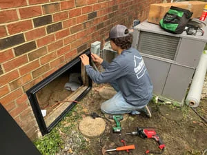 Technician installing vapor barrier and moisture control system in crawl space foundation area
