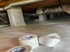 Crawl space with white vapor barrier, dehumidifiers, and HVAC ductwork installed