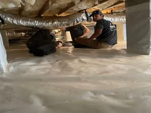 Crawl space with white vapor barrier installation and exposed foundation supports