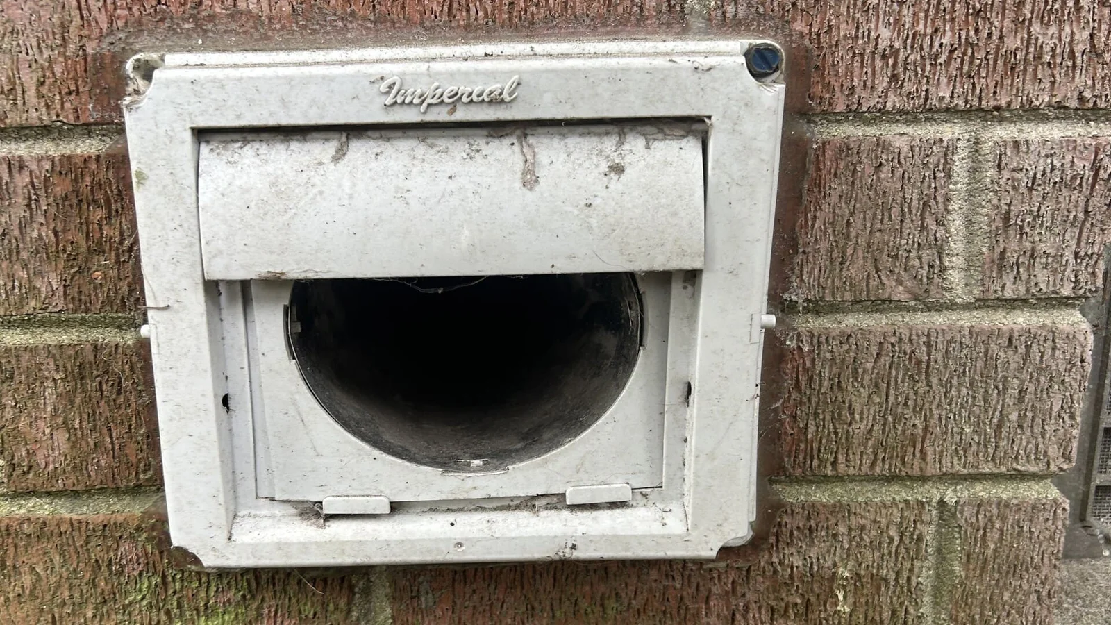 White Imperial dryer vent with damper installed in brick wall exterior