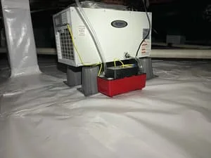 Crawl space with white vapor barrier and red dehumidifier unit installed