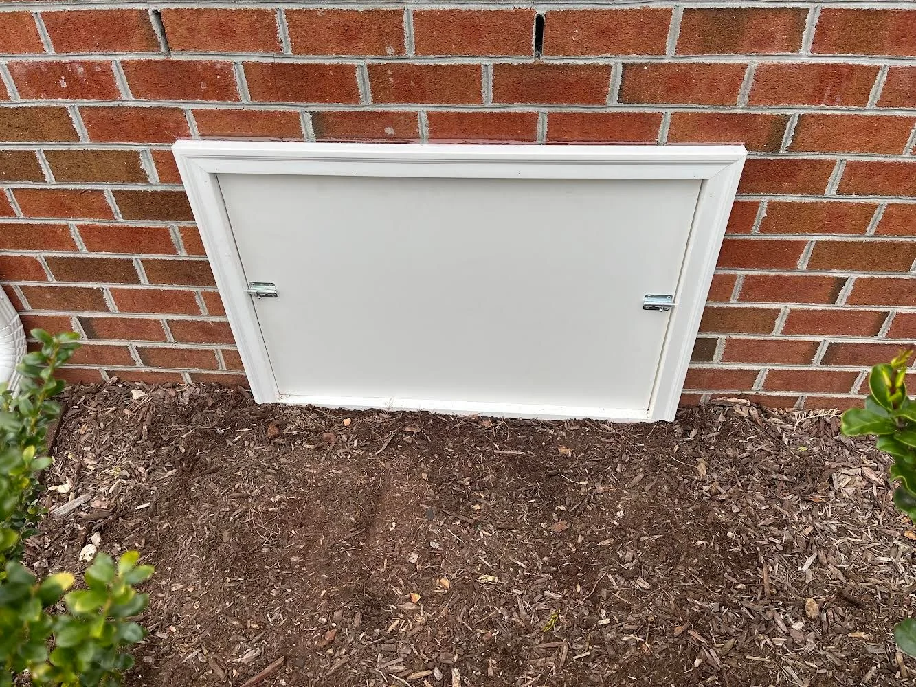 A newly installed airtight crawl space access door fitted flush against a concrete foundation wall on a residential home in Grimesland, NC. The door frame is sealed at the edges with no visible gaps, showing a clean and secure crawl space entry point.