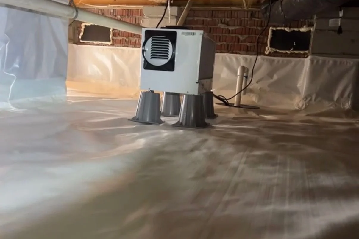 A newly installed crawl space foundation vent on a residential home in Grimesland, NC, with a clean metal cover fitted flush against the concrete block wall. The surrounding foundation shows no cracking or pest damage, and the crawl space interior is visible through the vent screen.