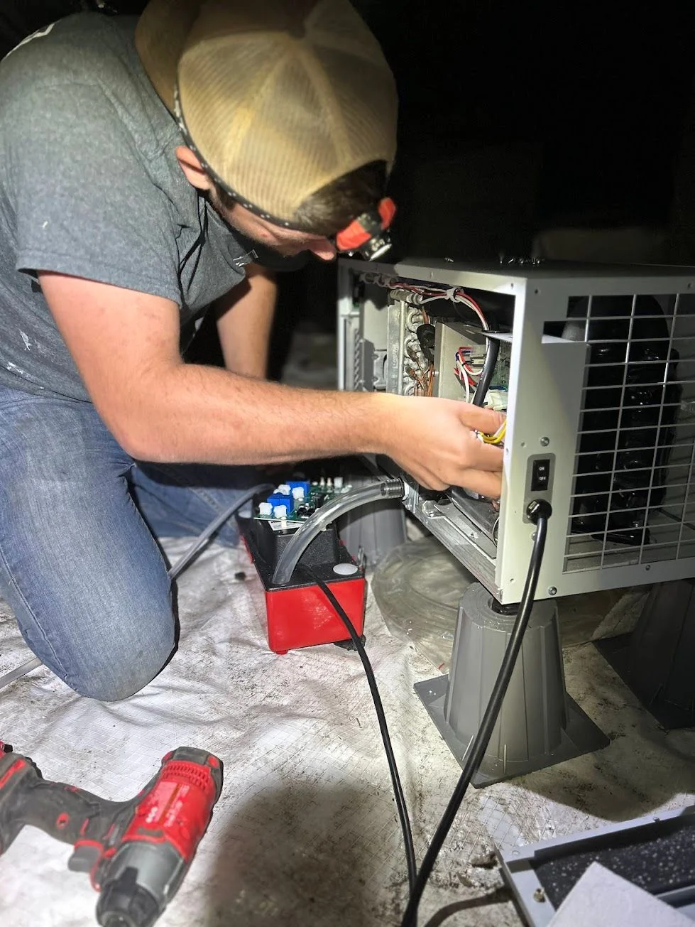 A crawl space dehumidifier installed beneath a Grimesland, NC home, with a drainage line routed away from the unit and dry, clean conditions visible on the surrounding floor joists and subfloor.